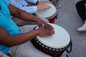 Drumming close-up, a black guy beats the rhythm on a djmba, a street musician performing in front of people, percussion sounds of nature. photo