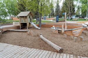 Children's playground of large sizes, sandbox in the yard, wooden boat for games, a house with a slide, rest with a child on the street. photo