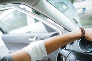 lesión a el mano el codo articulación es envuelto con un vendaje, el humano mano en el auto, el dolorido lugar, el protector vendaje, el estéril vendaje de el herida. foto