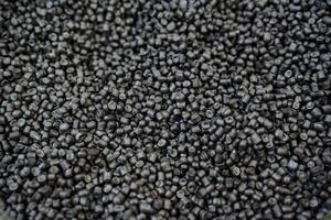 Black plastic chips are shot close-up, granules of polymeric material for the chemical industry, the structure of raw materials in a pile of small plastic. photo