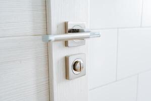 Open door to the room, chrome handle with lock, stylish modern door handle. Elements of the interior of the apartment. photo