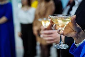 champán en un martini vaso, un niña participación un alcohólico bebida en su mano, celebrando un evento a un fiesta. foto