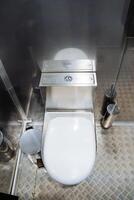 Anti-vandal toilet in a public place, metal hay, white toilet lid, stainless steel flush tanks. photo