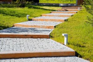 el peatonal camino en el parque es pavimentado con pavimentación piedras, un Roca camino, Roca pasos, registros mentira en el camino, el césped es cortado, el paisaje diseño de ciudad parques foto