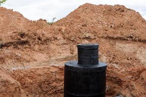 agujero de hombre, alcantarilla, hormigón estructura, circular anillo bloques, tubería reparar, negro alquitrán impermeabilización en el Bueno, la carretera obras. foto