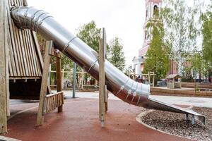 Round metal tube slide, children's playground outside, slide skiing, modern park for family holidays in the city. photo