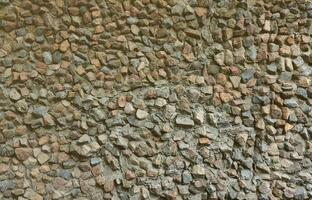 The texture of a strong stone wall of many concreted stones of various shapes photo