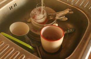 Stack of dirty dishes with food leftovers in the kitchen sink. Unwashed dishes photo