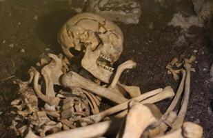 Skull and bones digged from pit in the scary graveyard of prisoners photo