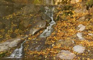 Beautiful waterfall between large rocks in autumn forest. Sofievskiy park in Uman, Ukraine photo