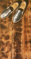 Original shiny shoes in disco style lie on a vintage wooden surface made from fried brown boards. Fashionable clothing retro accessory for discos and parties in the style of the eighties photo