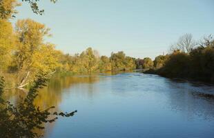 Beautiful autumn landscape with lake and multicoloral trees. Picturesque place with lake and tall trees photo