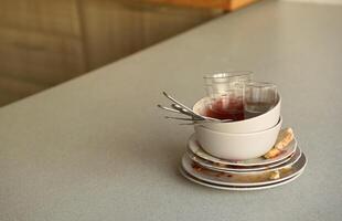 Stack of dirty dishes with food leftovers on the table after meal. Banquet ending concept. Unwashed dishes photo