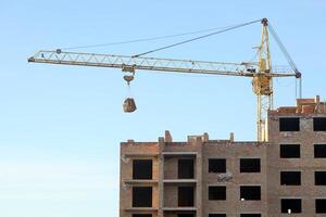 View of a large construction site with buildings under construction and multi-storey residential homes. Tower cranes in action on blue sky background. Housing renovation concept photo