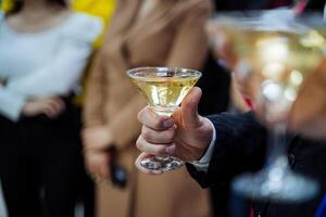 un del hombre mano sostiene un vaso de champán, un alcohol fiesta, bebida un martini desde un vaso. foto