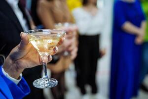 un mujer mano sostiene un vaso de vino, un martini en un vaso vaso, un fiesta con bebidas de alcohol, champán en el vaso. foto