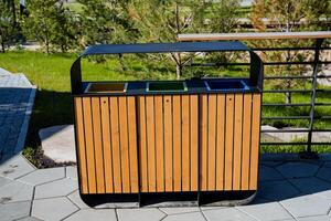 A dumpster stands on the sidewalk in a city park, an urn for sorting waste, care for the environment. Separate garbage collection. photo