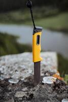 Hiking knife of a hiker hiker, vertical photo of the blade, knife hanging on a rope, lanyard for a knife.