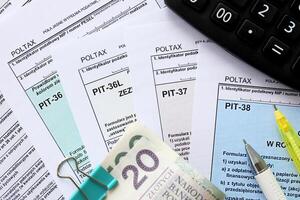 Declaration of the amount of earned income or incurred loss, PIT-36, PIT-36L, PIT-37 and PIT-38 tax forms on accountant table with pen and polish zloty money bills photo