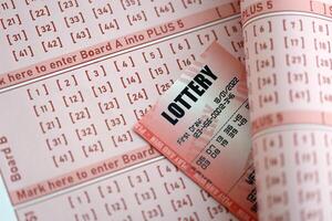 Red lottery ticket lies on pink gambling sheets with numbers for marking to play lottery photo