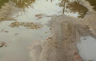 Photo of a fragment of a destroyed road with large puddles in rainy weather