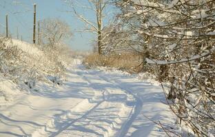 The road that lies parallel to the railway line is covered with snow on a sunny day after a heavy snowfall photo