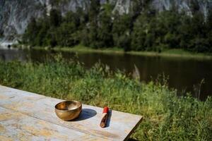 A copper Tibetan bowl stands on the table, a musical instrument singing a bowl, a beautiful landscape for meditation, yoga practice with music, a golden element. photo