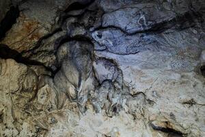 Stalactites hang on the ceiling of the cave, karst stains, underground formation. photo