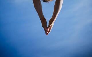 Hands reach for the sky, a triangle of human hands, body parts, blue sky, minimalism in life. photo