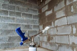 Construction gun emits spray foam, indoor construction, compressed air tool, steel foam tube. photo