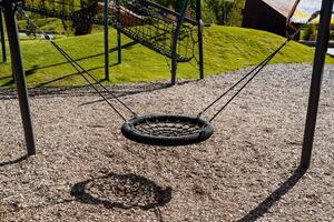 Swings for children hang on poles, a playground, a black rope braid, a place for walking with children, a round hanging swing. photo