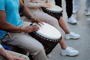 un fuerte muscular chico tambores en un djamba, un calle músico, bateristas golpear el ritmo de jazz en público, manos jugar en percusión. foto