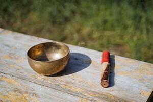 Musical instrument from Tibet bowl emitting vibrations and sound om, copper bowl singing, stick for striking metal, yoga attribute. photo