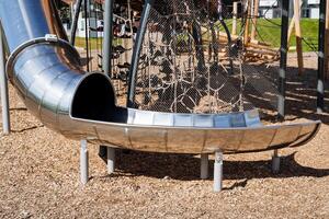 metal para niños redondo deslizar, patio de recreo para niños, ciudad parque en un moderno estilo, brillante cromo, inoxidable acero. foto