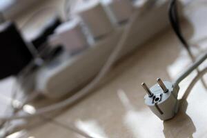 Overloaded power boards. Power strips with different electrical plugs on white floor photo