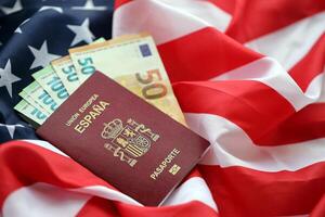 Red Spanish passport of European Union and money on United States national flag background photo