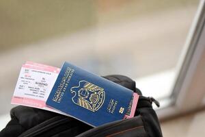 Blue United Arab Emirates passport with airline tickets on touristic backpack photo