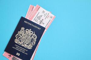 Blue British passport with airline tickets on blue background close up photo