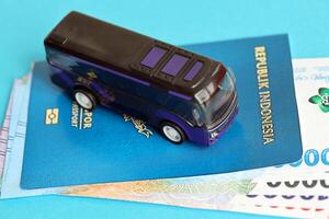 Blue Republic Indonesia passport with money and toy bus on blue background close up photo