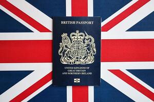 Blue British passport on national flag background close up photo