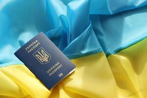 One Ukrainian biometrical passport on folded waving flag of Ukraine country photo