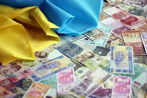 Ukrainian flag on many banknotes of different currency. Background of war funding photo