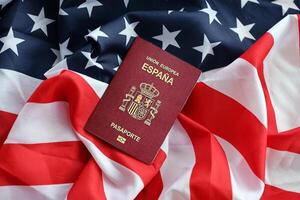 Red Spanish passport of European Union on United States national flag background close up photo