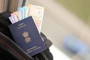 Blue Indian passport with money and airline tickets on touristic backpack photo