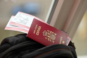 Red Spanish passport of European Union with airline tickets on touristic backpack photo