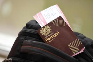 Red Portugal passport of European Union with airline tickets on touristic backpack photo