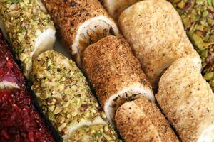 Rolls of turkish delight with many different flavors and fillings close up on table of vendors market photo