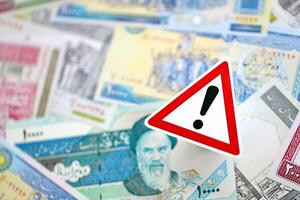 Small exclamation sign lies on pile of iranian money. Sanctions, ban or embargo concept photo