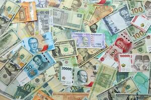 Many banknotes of different currency. Background of big amount of random money bills photo