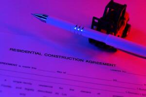 Residential construction agreement and toy forklift boomtruck sideloader car carries white pen on table photo